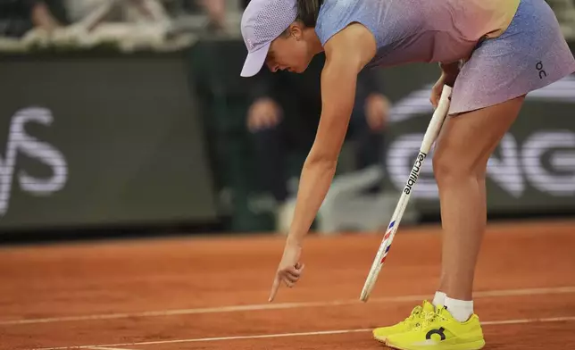 Poland's Iga Swiatek checks a mark on the clay as she plays against Aryna Sabalenka of Belarus during their semifinal match of the French Tennis Open at the Roland-Garros stadium in Paris, Thursday, June 5, 2025. (AP Photo/Thibault Camus)