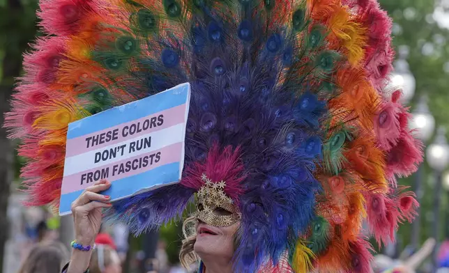 A participant wearing a colorful headdress holds up a sign during the World Pride parade, Saturday, June 7, 2025, in Washington. (AP Photo/Mark Schiefelbein)