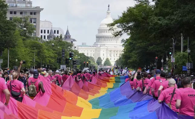 Participants carry a large pride flag during the World Pride parade with the U.S. Capitol in the background, Saturday, June 7, 2025, in Washington. (AP Photo/Mark Schiefelbein)
