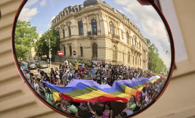 Participants in the Bucharest Pride Parade are reflected in a traffic safety mirror in Bucharest, Romania, Saturday, June 7, 2025. (AP Photo/Vadim Ghirda)