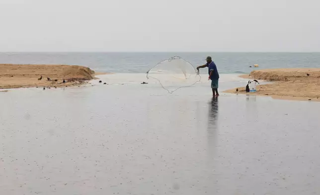 A fisherman throws a net in Puerto Escondido, Oaxaca state, Mexico, before the arrival of Hurricane Erick, Wednesday, June 18, 2025. (AP Photo/Luis Alberto Cruz)