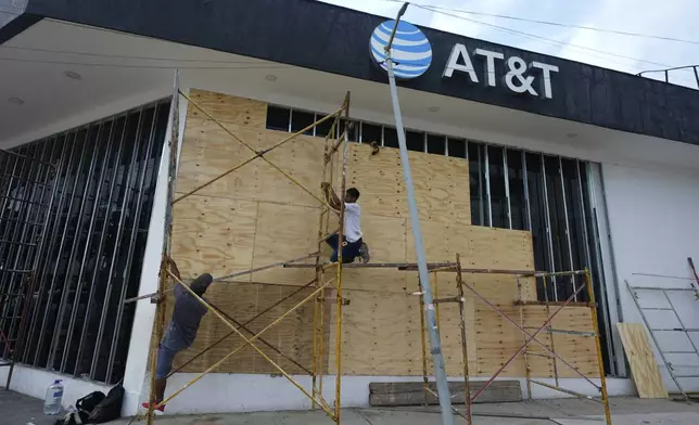 Workers board up a storefront as they prepare for the arrival of Hurricane Erick, in Acapulco, Mexico, Wednesday, June 18, 2025. (AP Photo/Fernando Llano)