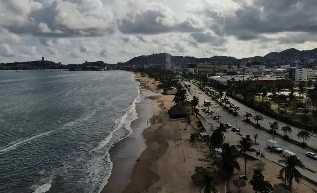 Tourists stroll along the beach shore before the arrival of Hurricane Erick, in Acapulco, Mexico, Wednesday, June 18, 2025. (AP Photo/Fernando Llano)