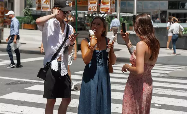 Woman takes a bite of an ice cream cone during a heatwave on Tuesday, June 24, 2025, in New York. (AP Photo/Olga Fedorova)