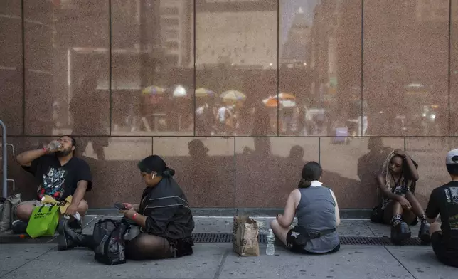 Fans of Japanese band "Baby Metal" cool off with water and wet wipes as they line up to see the show during a heatwave on Tuesday, June 24, 2025, in New York. (AP Photo/Olga Fedorova)