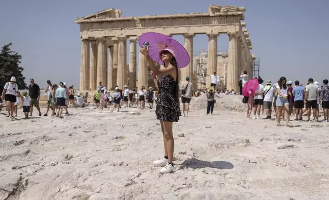 FILE - A woman takes a selfie in front of Parthenon temple atop of the ancient Acropolis hill during a heat wave in Athens, Greece, July 21, 2023. (AP Photo/Petros Giannakouris, File)