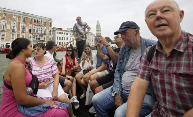 FILE - Tourists sit in a gondola during a short crossing of a canal, in Venice, Italy, Wednesday, Sept. 13, 2023. (AP Photo/Luca Bruno, File)