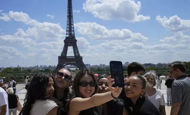FILE - Tourists pose for a selfie with the Eiffel Tower in background, Thursday, July 6, 2023 in Paris. (AP Photo/Michel Euler, File)