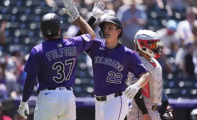 Colorado Rockies' Braxton Fulford, left, congratulates Mickey Moniak as he crosses home plate after hitting a three-run home run off Arizona Diamondbacks starting pitcher Brandon Pfaadt in the fifth inning of a baseball game Sunday, June 22, 2025, in Denver. (AP Photo/David Zalubowski)