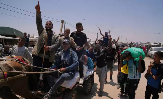 Palestinians wave to the camera while carrying bags containing food and humanitarian aid packages delivered by the Gaza Humanitarian Foundation, a U.S.-backed organization, in Rafah, southern Gaza Strip, Tuesday, June 10, 2025. (AP Photo/Abdel Kareem Hana)