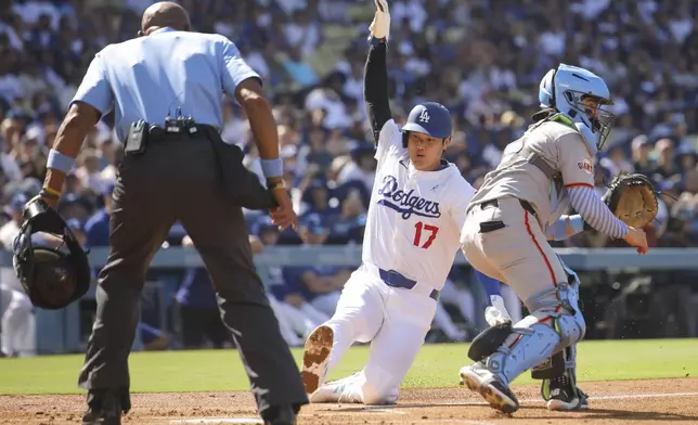 Los Angeles Dodgers designated hitter Shohei Ohtani (17) slides into home plate to score as San Francisco Giants catcher Logan Porter, right, looks on during the first inning of a baseball game in Los Angeles, Sunday, June 15, 2025. (AP Photo/Jessie Alcheh)