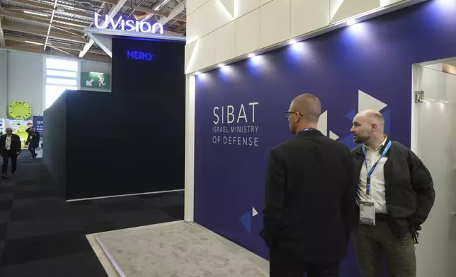 People stand by a black wall that blocks the Israeli pavilions has been erected at the Paris Air Show , Monday, June 16, 2025 in Le Bourget, north of Paris. (AP Photo/Michel Euler)