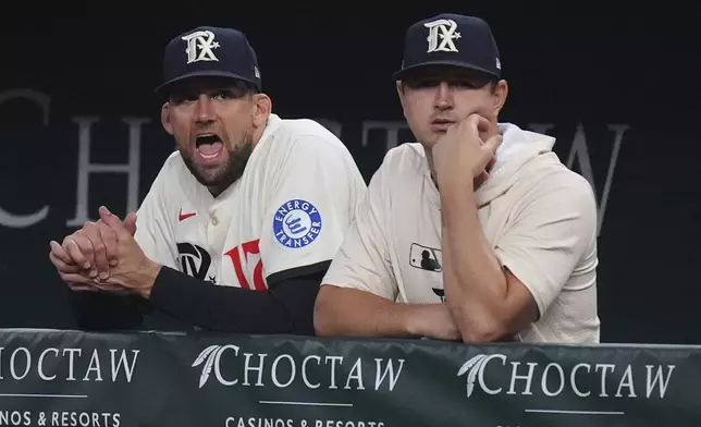 Texas Rangers starting pitcher Nathan Eovaldi, left, looks on from the dugout with teammate Tyler Mahle, right, during the fourth inning of a baseball game against the Seattle Mariners, Friday, June 27, 2025, in Arlington, Texas. (AP Photo/LM Otero)