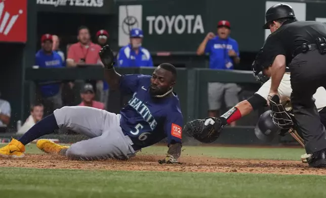 Seattle Mariners' Randy Arozarena (56) scores against Texas Rangers catcher Kyle Higashioka, back right, during the 12th inning of a baseball game, Friday, June 27, 2025, in Arlington, Texas. (AP Photo/LM Otero)