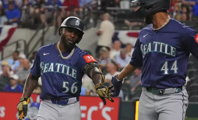 Seattle Mariners Randy Arozarena (56) gets a congratulations for the sacrifice fly that scored teammate Julio Rodríguez (44) during the third inning of a baseball game against the Texas Rangers, Friday, June 27, 2025, in Arlington, Texas. (AP Photo/LM Otero)