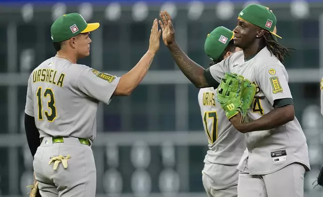 Athletics' Lawrence Butler (4) and Gio Urshela (13) celebrate after a baseball game against the Houston Astros Saturday, July 26, 2025, in Houston. (AP Photo/David J. Phillip)
