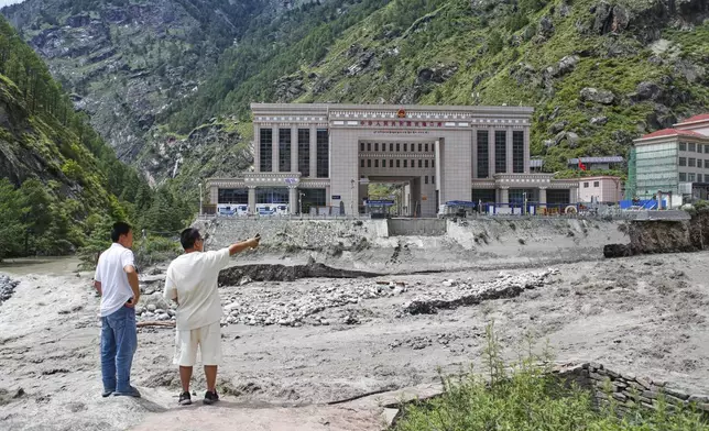 A man points to the Chinese side after Friendship bridge, a key bridge connecting the country with China over the Bhotekoshi River was swept away in monsoon rain at Rasuwagadi, 120 kilometers (75 miles) north of the capital, Kathmandu, Nepal, Wednesday, July, 9, 2025. (AP Photo/Sujan Gurung)