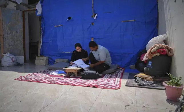 Sarah Qanan studies with her father, Ibrahim, in their family's tent in Khan Younis, Gaza Strip, on June 28, 2025. (AP Photo/Abdel Kareem Hana)