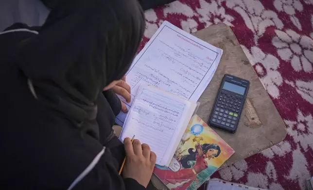 Sarah Qanan studies inside her family's tent in Khan Younis, Gaza Strip, on June 28, 2025. (AP Photo/Abdel Kareem Hana)