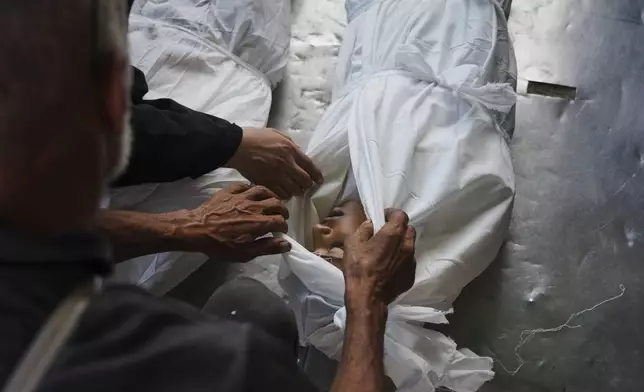 Relatives look at the body of Palestinian child Abdullah al-Rantisi, 11, killed by an Israeli military bombardment, in Deir al-Balah, central Gaza Strip, Monday, July 21, 2025. (AP Photo/Abdel Kareem Hana)