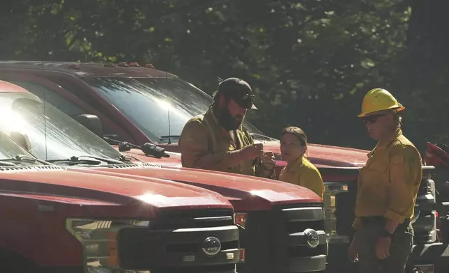 Idaho Department of Lands firefighters stand near a roadblock close to the scene the day after a shooter ambushed and killed multiple firefighters responding to a wildfire at Canfield Mountain Monday, June 30, 2025, in Coeur D'Alene, Idaho. (AP Photo/Lindsey Wasson)