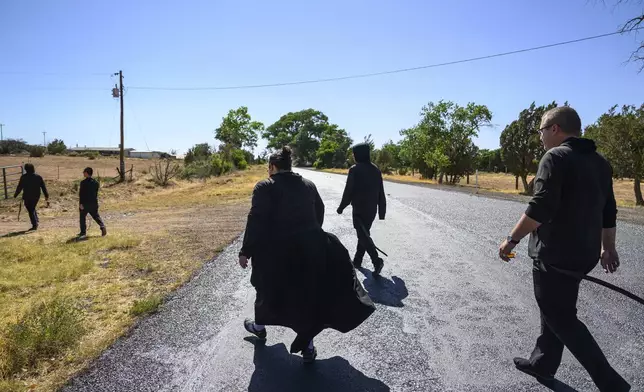 League of the Blessed Sacrament members walk to their animal farm in Concho, Ariz., Saturday, June 21, 2025. Bishop James S. Wall has ordered the lay group of young Catholics to leave parish housing and stop leading liturgy and teaching in the region’s Catholic school. (AP Photo/Roberto E. Rosales)