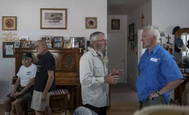 John Bunn, center, speaks to Tom Toepfer during a gathering to discuss the Diocese of Gallup’s decision regarding the League of the Blessed Sacrament, a lay group of young Catholics who have been ordered to leave parish housing, stop leading liturgy and teaching in the region’s Catholic school in Concho, Ariz., Saturday, June 21, 2025. (AP Photo/Roberto E. Rosales)