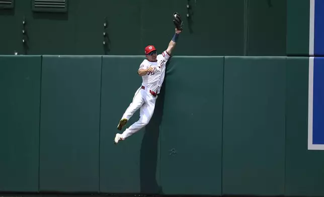 Washington Nationals center fielder Jacob Young makes a a leaping catch at he wall on a fly ball by Cincinnati Reds' Will Benson for an out during the eighth inning of a baseball game, Wednesday, July 23, 2025, in Washington. (AP Photo/Nick Wass)