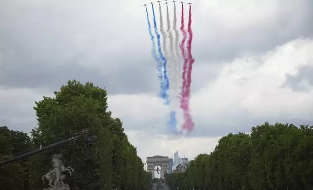 Jets from the acrobatic Patrouille de France fly over the Champs-Elysees avenue during the Bastille Day parade, Monday, July 14, 2025 in Paris. (AP Photo/Christophe Ena)