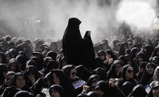 Iranian Shiite Muslims mourn in a ceremony as water is being sprayed for heat management, in Tehran, Iran, Friday, July 4, 2025, ahead of Ashoura, a remembrance of the 7th-century martyrdom of the Prophet Muhammad's grandson, Hussein, who was killed in a battle in Karbala in present-day Iraq. (AP Photo/Vahid Salemi)