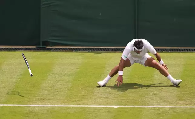 Nikoloz Basilashvili of Georgia falls during his first round men's singles match against Lorenzo Musetti of Italy at the Wimbledon Tennis Championships in London, Tuesday, July 1, 2025.(AP Photo/Joanna Chan)