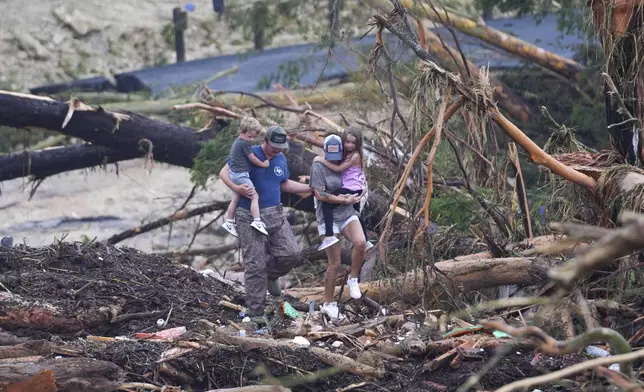 People climb over debris on a bridge atop the Guadalupe River after a flash flood swept through the area Saturday, July 5, 2025, in Ingram, Texas. (AP Photo/Julio Cortez)
