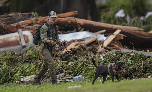 Officials comb through the banks of the Guadalupe River after a flash flood swept through the area Saturday, July 5, 2025, in Hunt, Texas. (AP Photo/Julio Cortez)