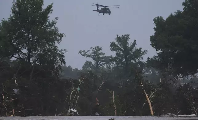 A helicopter flies over the Guadalupe River after a flash flood swept through the area, Friday, July 4, 2025, in Kerrville, Texas. (AP Photo/Eric Gay)