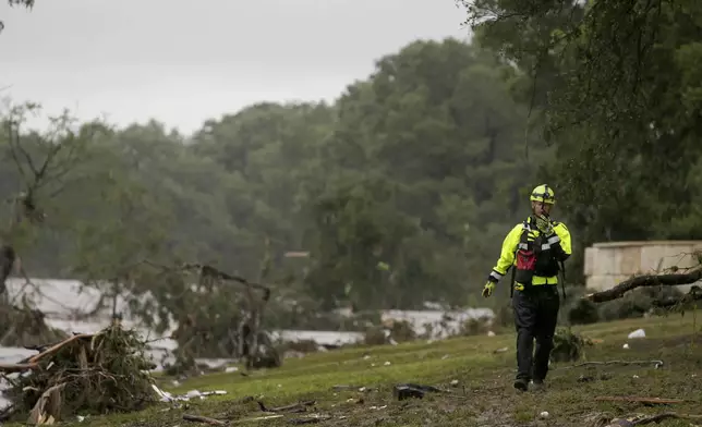 CORRECTS DAY - A Kerrville firefighter works the scene near the banks of the Guadalupe River after people were swept away by flooding in Ingram, Texas, Friday, July 4, 2025. (Michel Fortier/The San Antonio Express-News via AP)