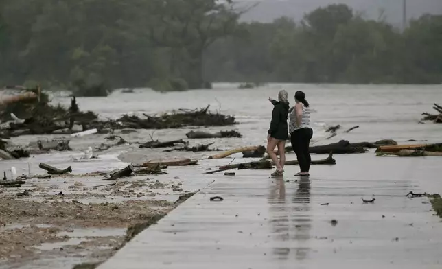 CORRECTS DAY - Two employees who wished to remain nameless, from HTR RV Park, look over the area where dozens of trailers were swept away by rising flood waters on the Guadalupe River in Ingram, Texas, Friday, July 4, 2025. (Michel Fortier/The San Antonio Express-News via AP)