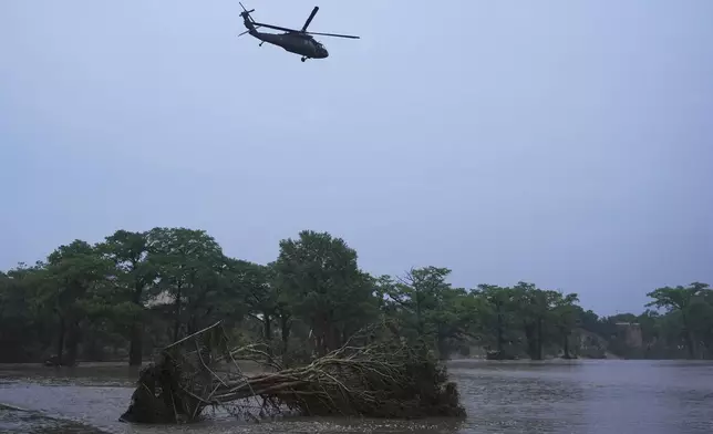 A helicopter flies over the Guadalupe River after a flash flood swept through the area, Friday, July 4, 2025, in Kerrville, Texas. (AP Photo/Eric Gay)