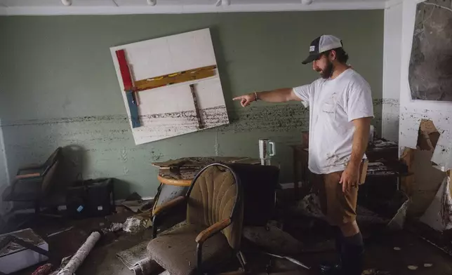 Garrett Burleson shows the damage to the office of his family's architectural business as a dirt line shows the extent of the flooding that the building faced, in Ingram on Friday July 4, 2025. (Christopher Lee/The San Antonio Express-News via AP)