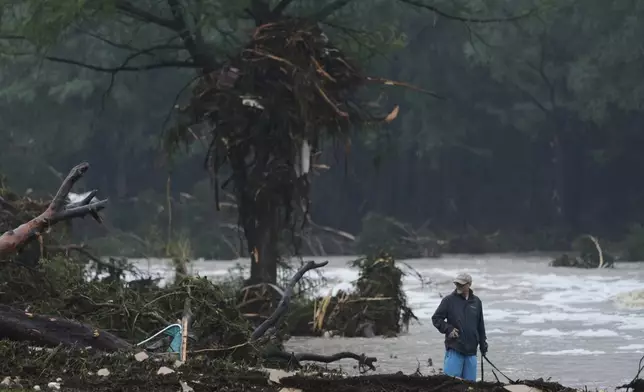 A man surveys debris along the Guadalupe River after a flash flood struck the area, Friday, July 4, 2025, in Kerrville, Texas. (AP Photo/Eric Gay)