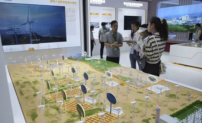 Exhibitors attend visitors at the China Resources Power Holdings Company Limited exhibition booth showcasing its wind turbines farm during the 3rd China International Supply Chain Expo at the China International Exhibition Center, in Beijing on July 17, 2025. (AP Photo/Andy Wong)