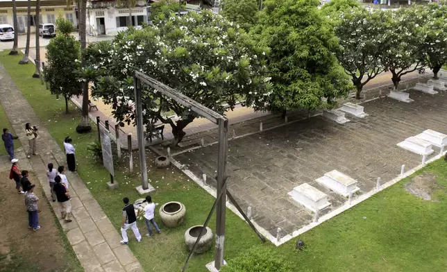 FILE - Tourists take their tour at the grave side in the former Pol Pot 's notorious S-21 prison, known Tuol Sleng genocide museum in Phnom Penh, Cambodia, Sunday, July 19, 2009. (AP Photo/Heng Sinith, File)