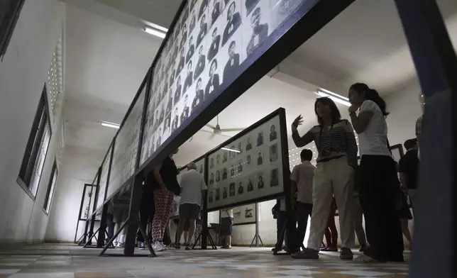 FILE - Tourists look at portraits of genocide victims in Khmer Rouge regime at the Tuol Sleng Genocide Museum, formerly the most notorious Khmer Rouge prison, in Phnom Penh, Cambodia, on July 10, 2014. (AP Photo/Heng Sinith, File)