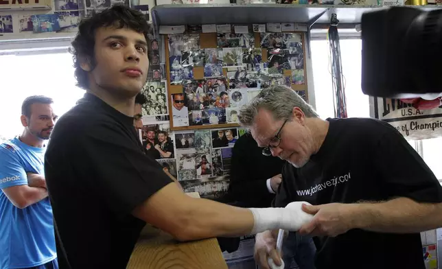 FILE - Boxer Julio Cesar Chavez Jr., left, has his hand taped by trainer Freddie Roach before a media workout in Los Angeles, May 18, 2011. (AP Photo/Jae C. Hong, File)