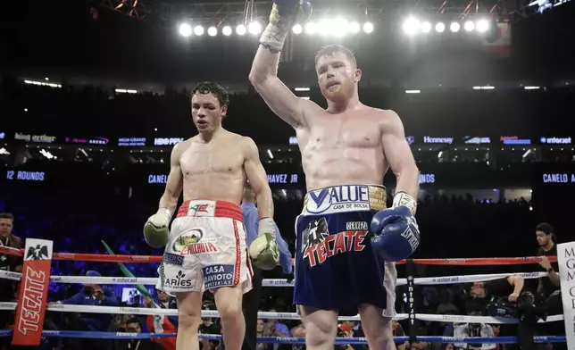 FILE - Canelo Alvarez, of Mexico, right, celebrates after defeating Julio Cesar Chavez Jr., of Mexico, in a catch weight boxing match in Las Vegas, May 6, 2017. (AP Photo/John Locher, File)