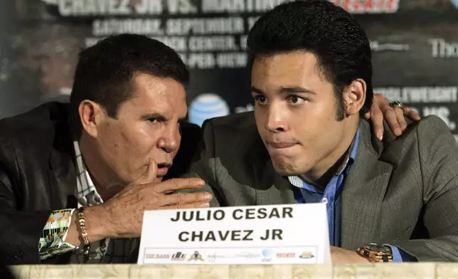 FILE - Julio Cesar Chavez Jr., right, of Mexico, talks with his father, legendary boxer Julio Cesar Chavez, left, at a news conference to promote his upcoming middleweight championship boxing match with Sergio Martinez, of Argentina, in Los Angeles, July 10, 2012. (AP Photo/Reed Saxon, File)