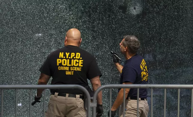 Members of NYPD Crime Unit examine a door with bullet holes at the scene of Monday's deadly shooting, Tuesday, July 29, 2025, in New York. (AP Photo/Yuki Iwamura)