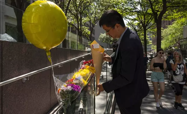 A person leaves flowers at a make shift memorial outside scene of Monday's deadly shooting, Tuesday, July 29, 2025, in New York. (AP Photo/Yuki Iwamura)