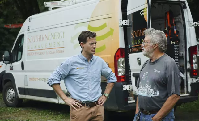 James Asbill, right, speaks with Will Etheridge, CEO of Southern Energy Management, as solar panels are installed on Asbill's home in Chapel Hill, N.C., Wednesday, July 2, 2025. (AP Photo/Allen G. Breed)