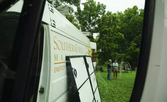 James Asbill, left, speaks with Will Etheridge, CEO of Southern Energy Management, as solar panels are installed on Asbill's home in Chapel Hill, N.C., Wednesday, July 2, 2025. (AP Photo/Allen G. Breed)