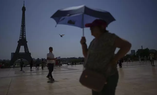 FILE - People walk at Trocadero plaza near the Eiffel Tower during a heat wave July 2, 2025, in Paris. (AP Photo/Christophe Ena, File)